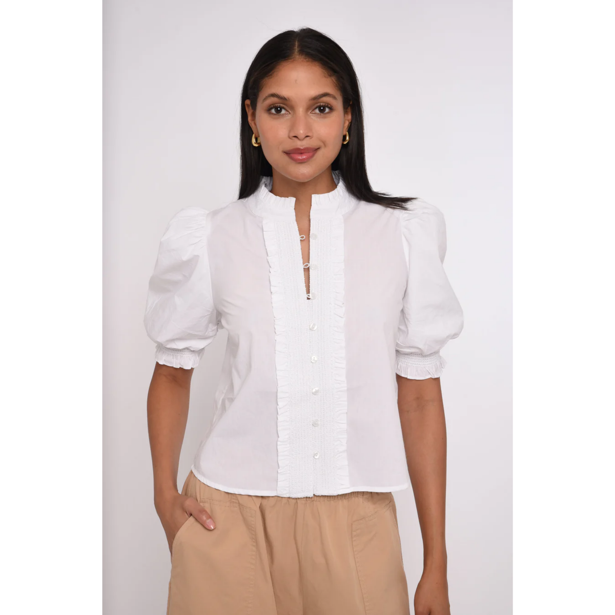 Woman wearing a white blouse with puffed sleeves against a plain background