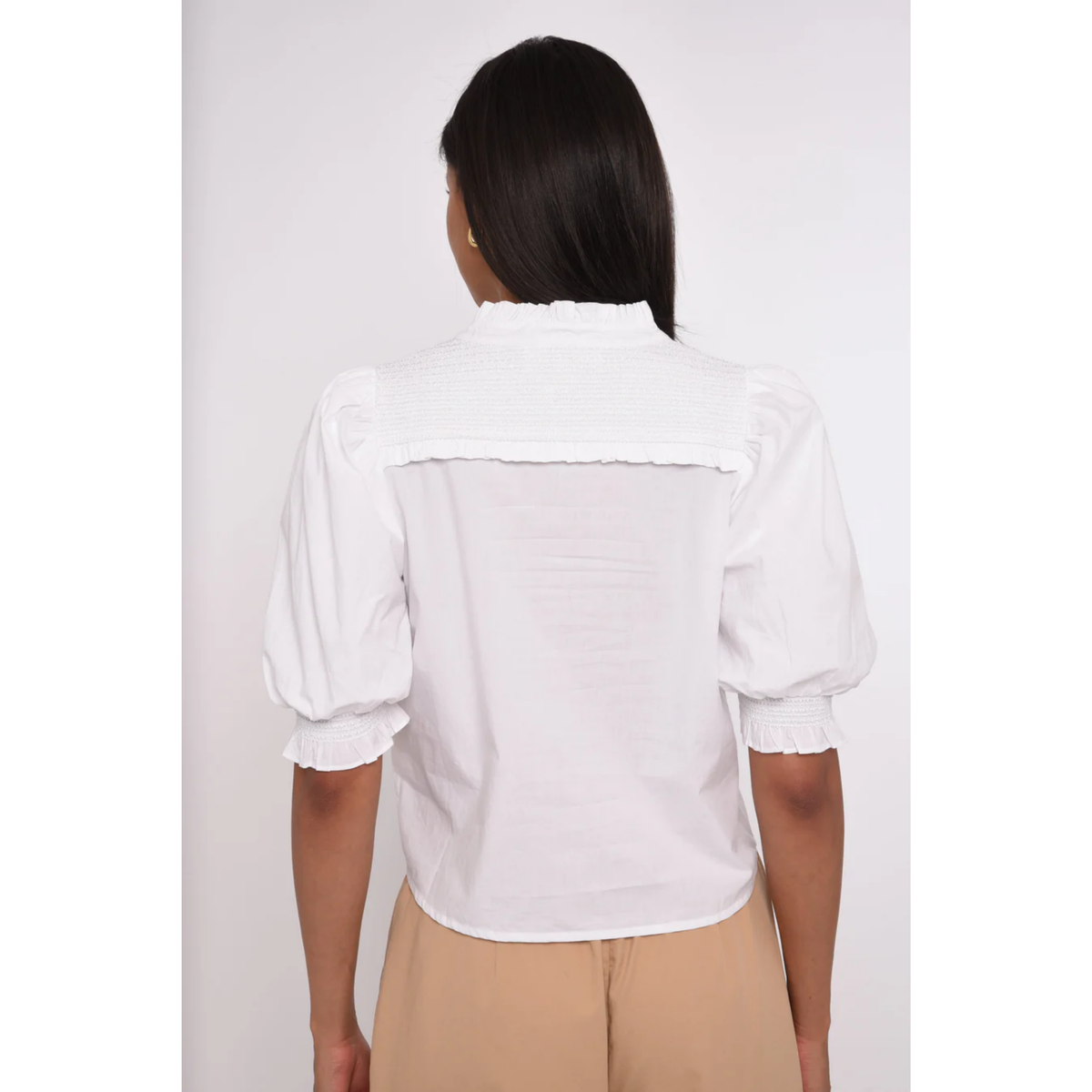 Person wearing a white blouse with puffed sleeves on a plain background