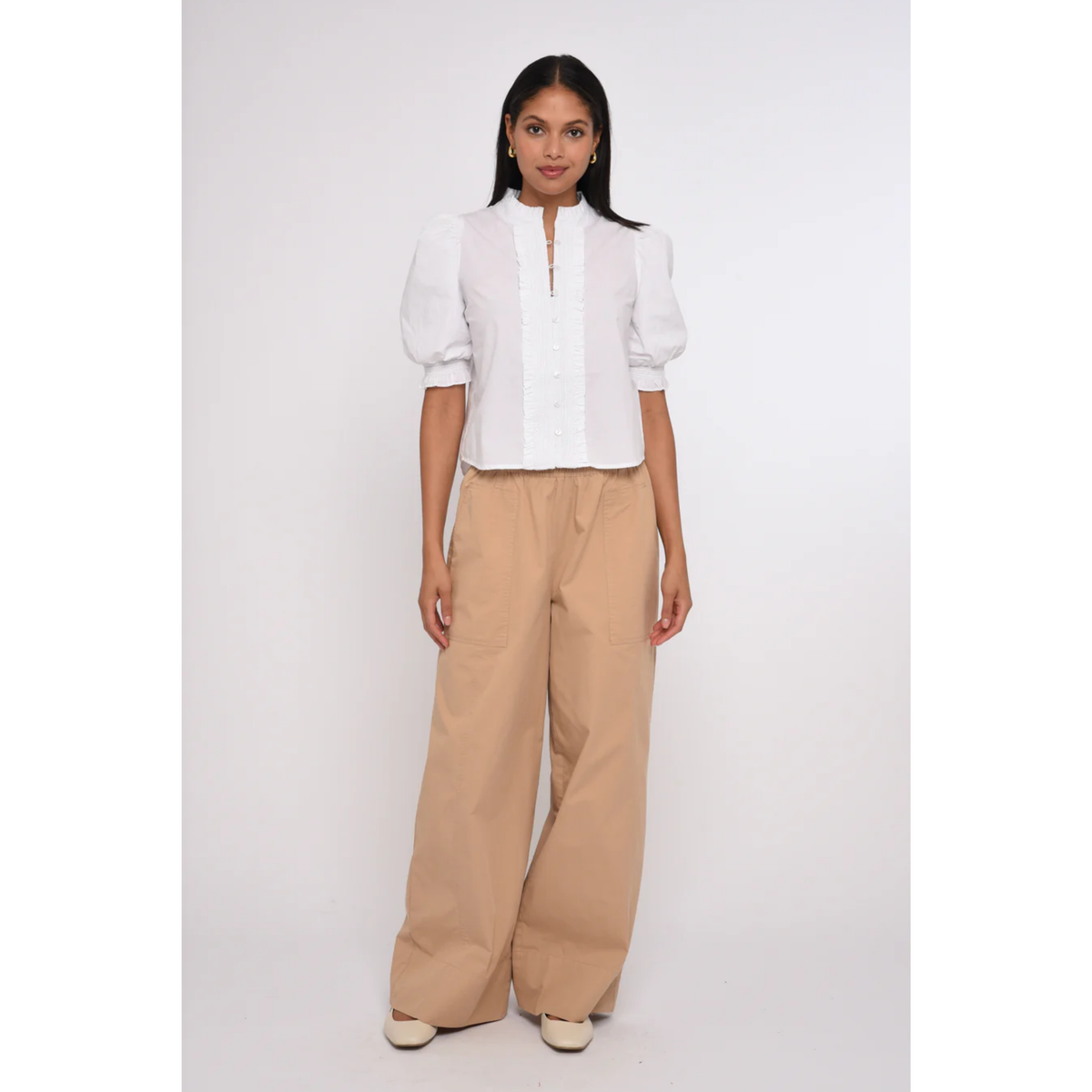 Woman wearing a white blouse and beige pants on a white background